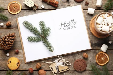 Notebook with text HELLO WINTER, Christmas branches and treats on wooden back Stock Photos