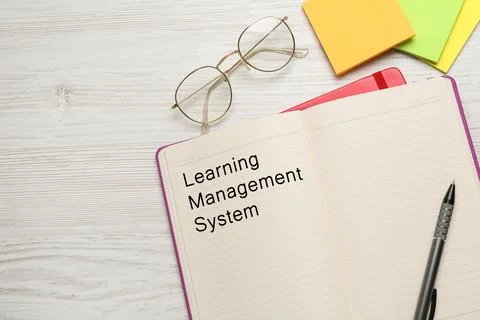 Notebook with text Learning Management System on white wooden table, flat l.. Stock Photos