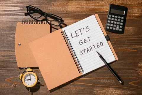 Notebook with text LET'S GET STARTED, alarm clock, calculator and eyeglasses  Stock Photos