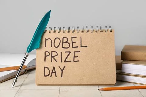 Notebook with text NOBEL PRIZE DAY, nib pen and books on tile against grey ba Stock Photos