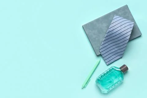 Notebook with tie, perfume bottle and pen on turquoise background Stock Photos