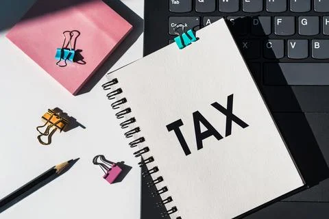 Notebook with tools and notes about TAX lies on laptop. Financial and busines Stock Photos