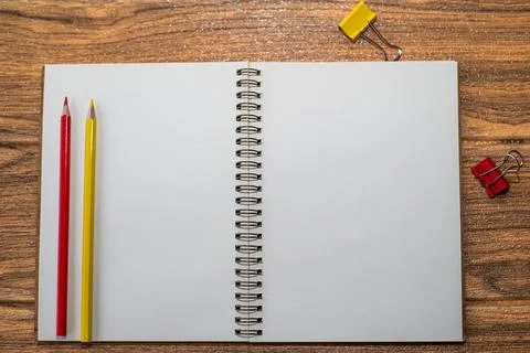 Notebook with white sheet open on the table, with red and yellow supplies nex Stock Photos