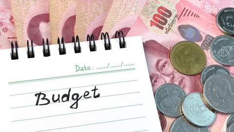 A notebook with the word "Budget" written on it, Thai money and coins close-up Stock Photos