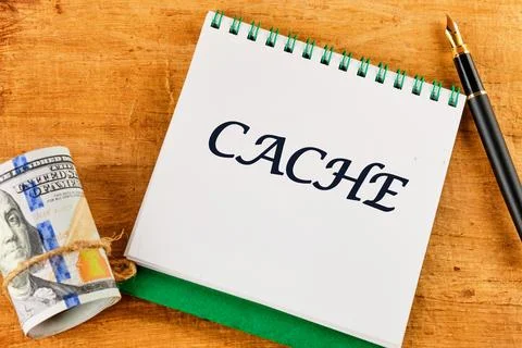 A notebook with the word CACHE written prominently is placed on a wooden tabl Stock Photos