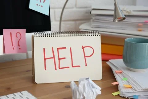 Notebook with word Help, computer and stationery on wooden table at workplace Stock Photos
