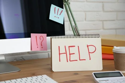 Notebook with word Help, computer and stationery on wooden table at workplace Stock Photos
