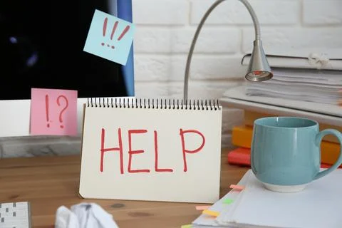 Notebook with word Help, computer and stationery on wooden table at workplace Stock Photos