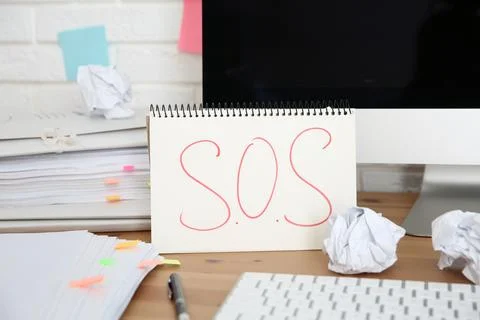 Notebook with word SOS, computer and stationery on wooden table at workplace 스톡 사진