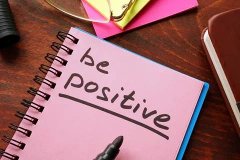 Notebook with the words Be positive on the table. Stock Photos