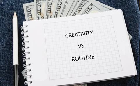 A notebook with the words creativity vs routine sits on a surface. Dollar bil Stock Photos