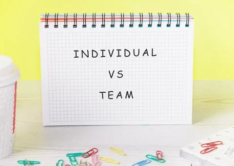 A notebook with the words individual vs team written on a grid page is displa Stockfoto's
