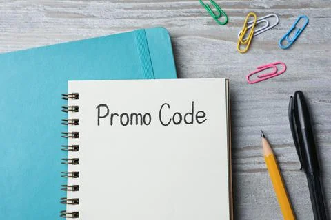 Notebook with words Promo Code and stationery on wooden table, flat lay Foto stock