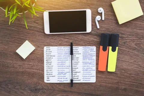 Notebook for writing foreign words dictionary, smartphone, wireless headpho.. Stock Photos