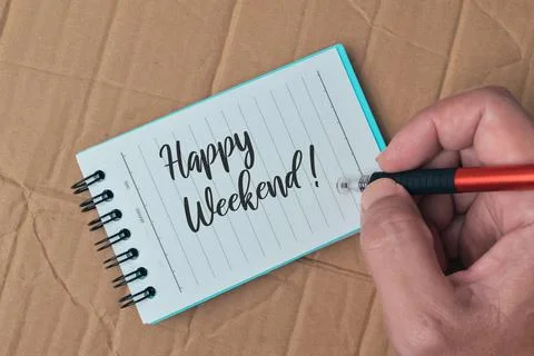 Notebook written with HAPPY WEEKEND! over cork board background. Stock Photos