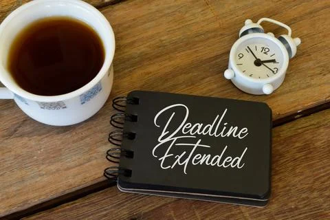 Notebook written with text DEADLINE EXTENDED over wooden background. Stock Photos