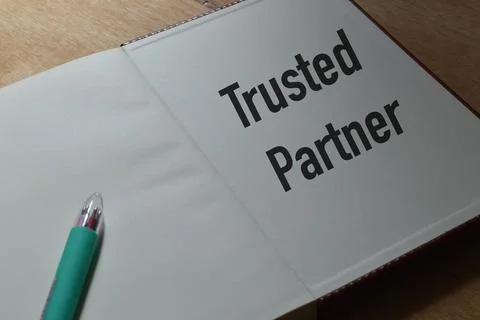 Notebook written with text TRUSTED PARTNER over wooden background. Foto stock