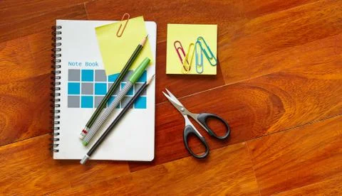 Notebook with yellow sticky note clipped on the cover page, pencils, scissor Photos