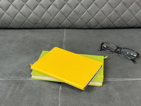 Notebooks with glasses on gray sofa Foto stock