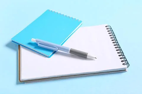 Notebooks with pen on blue background Stock Photos