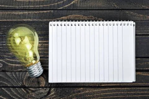 Notepad and bulb on table Photos