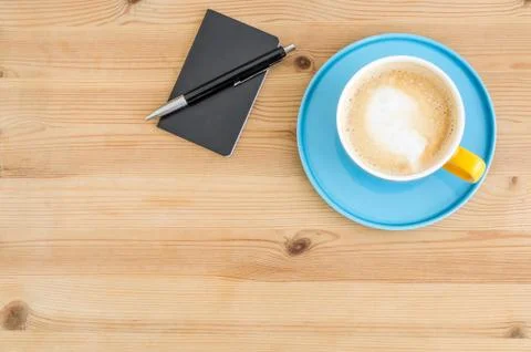 Notepad and pen next to a coffee in a colorful cup Stock Photos
