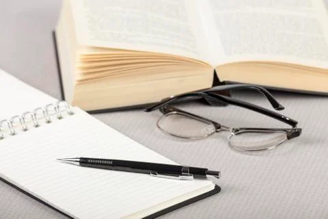 Notepad and pen on a table with a book Stock Photos