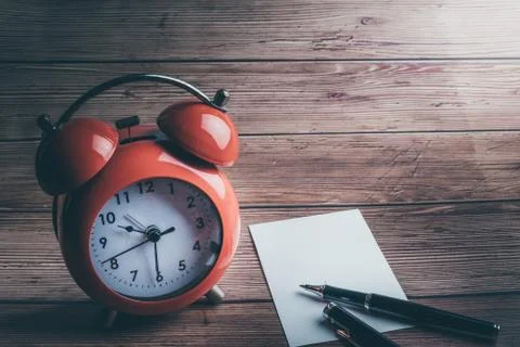 Notepad with blank pages and copy space and red alarm clock on wooden backgro Stock Photos