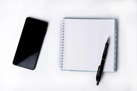 Notepad, blank sheet and phone on a white background. Top view. Stock Photos