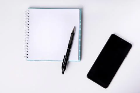 Notepad, blank sheet and phone on a white background. Top view. Stock Photos