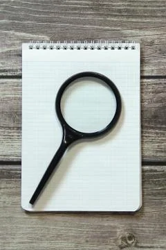 Notepad with a blank white sheet in a checker paper lies with magnifying glas Stock Photos