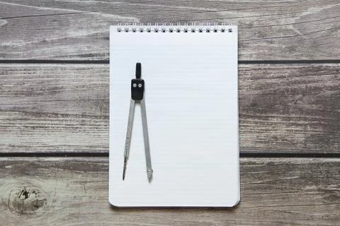 Notepad with a blank white sheet in a checker paper with compass lies on the  Stock Photos