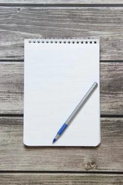 Notepad with a blank white sheet in a checker paper with ball pen lies on the Stock Photos