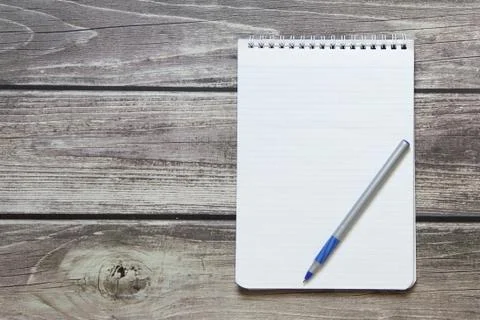 Notepad with a blank white sheet in a checker paper with ball pen lies on the Stock Photos