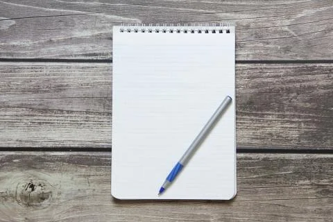 Notepad with a blank white sheet in a checker paper with ball pen lies on the Stock Photos