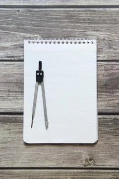 Notepad with a blank white sheet in a checker paper with compass lies on the  Foto stock