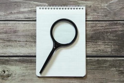 Notepad with a blank white sheet in a checker paper lies with magnifying glas Stock Photos