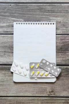 Notepad with a blank white sheet in a checker paper with pills in a blister l Stock Photos