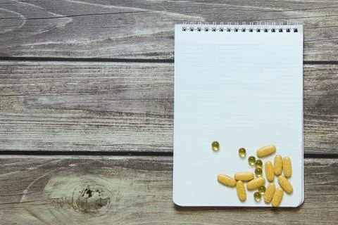 Notepad with a blank white sheet in a checker paper with pills lies on the ba Stock Photos