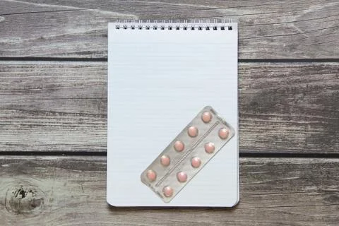 Notepad with a blank white sheet in a checker paper with pills in a blister l Stock Photos