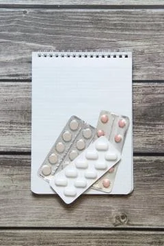 Notepad with a blank white sheet in a checker paper with pills in a blister l Stock Photos