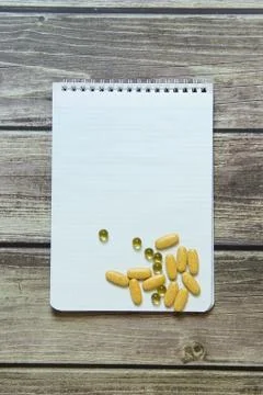Notepad with a blank white sheet in a checker paper with pills lies on the ba Stock Photos