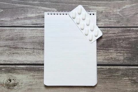 Notepad with a blank white sheet in a checker paper with pills in a blister l Foto stock