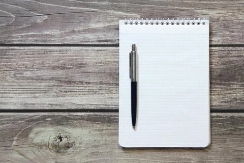 Notepad with a blank white sheet in a checker paper with ball pen lies on the Stock Photos