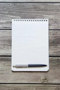 Notepad with a blank white sheet in a checker paper with ball pen lies on the Foto stock