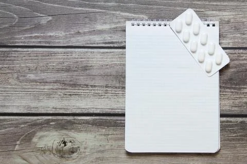 Notepad with a blank white sheet in a checker paper with pills in a blister l Foto stock