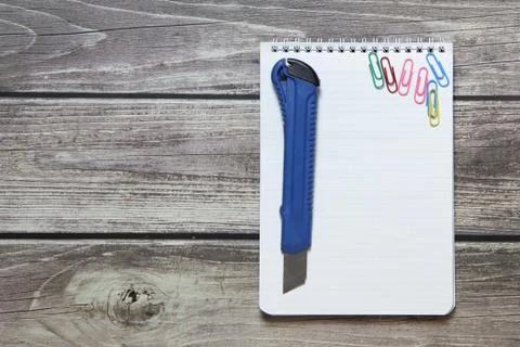 Notepad with a blank white sheet in a checker paper and with stationery knife Stock Photos