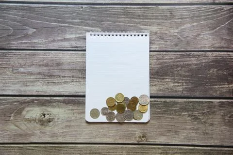 Notepad with a blank white sheet in a checker paper with russian coins lies o Stock Photos