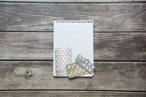Notepad with a blank white sheet in a checker paper with pills in a blister l Stock Photos