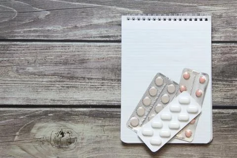 Notepad with a blank white sheet in a checker paper with pills in a blister l Stock Photos